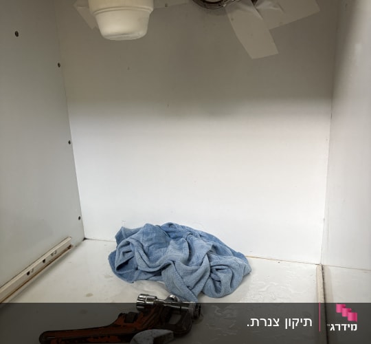 כלי עבודה וצינור מתחת לכיור